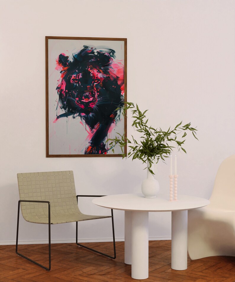 May include: A white round table with four white cylindrical legs. A vase with green leafy branches and a pink candle holder are on the table. A light brown woven chair with a black metal frame is in the foreground. A framed abstract painting of a pink and black animal is on the wall.