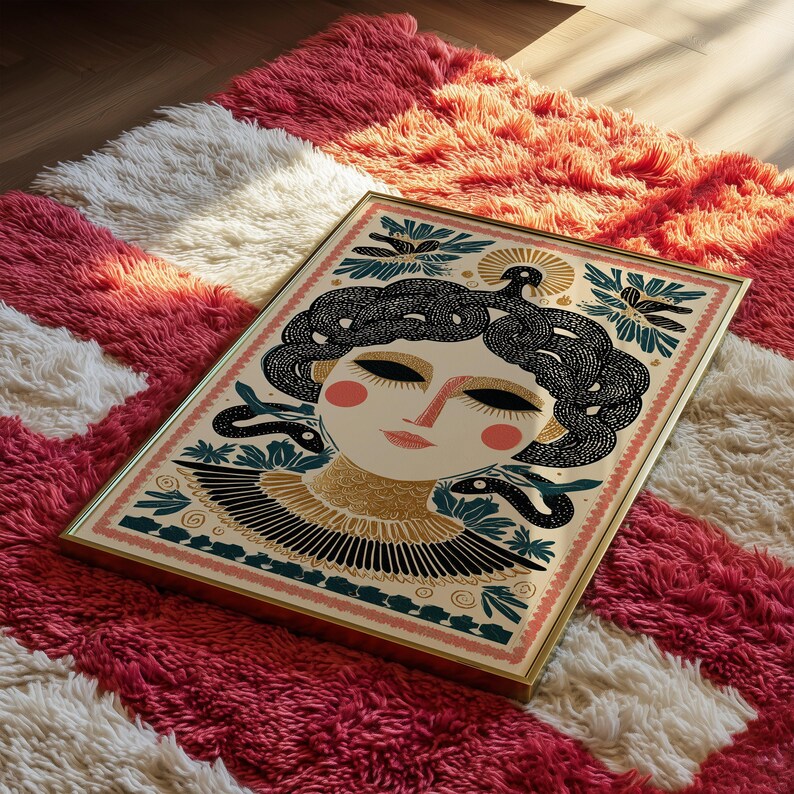May include: Framed art print featuring a stylized illustration of a woman with snakes for hair, in a gold frame. The artwork has a cream background with black, gold, and teal accents. The print is resting on a red, white, and pink shag rug.