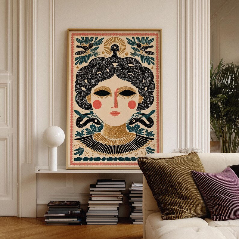May include: A framed art print featuring a stylized illustration of a woman with black hair styled with snakes. The artwork has a beige background with a pink border and includes floral and snake motifs. The woman has red cheeks and lips.