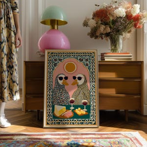 May include: Framed art print featuring two ducks wearing sunglasses, set against a pink backdrop with a sun. The ducks are depicted with patterned scarves, enjoying wine and cheese. The artwork is framed in a gold border.