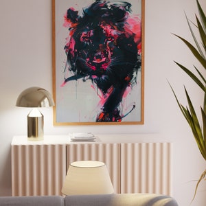 May include: A framed abstract painting of a lion's head in shades of pink, black, and white. The lion's eyes are a deep black, and its mane is a vibrant pink. The painting is set against a white background.