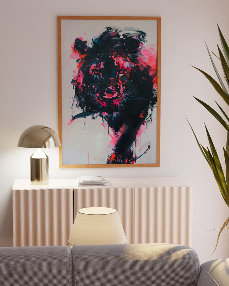 May include: A framed abstract painting of a lion's head in shades of pink, black, and white. The lion's eyes are a deep black, and its mane is a vibrant pink. The painting is set against a white background.