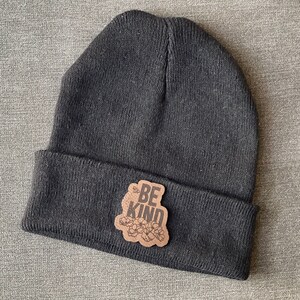 May include: Black beanie with a brown leather patch that says "Be Kind" with a floral design.