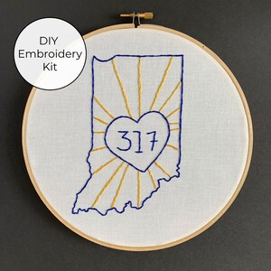 May include: DIY embroidery kit featuring a blue outline of the state of Indiana with a gold sunburst design and a blue heart with the number 317 inside.