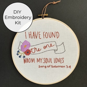 May include: DIY embroidery kit featuring a white hoop with the text "I HAVE FOUND the one WHOM MY SOUL LOVES Song of Solomon 3:4" embroidered in red thread. The hoop is decorated with pink, red, and blue embroidered flowers.