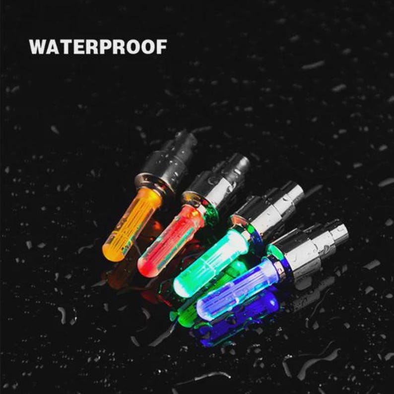 May include: A close-up shot of several multi-colored LED lights. The lights are cylindrical with a silver base and a colored, transparent top. The colors include orange, red, green, and blue. The word "WATERPROOF" is printed in white at the top.