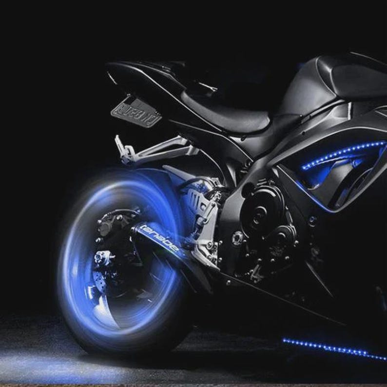 May include: A black sport motorcycle with blue LED lighting accents. The motorcycle's wheels and undercarriage are illuminated with bright blue lights, creating a striking visual effect against the dark background. The image highlights the sleek design and custom modifications.