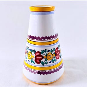May include: A conical ceramic vase with a white base featuring hand-painted horizontal bands in yellow and purple. The central section displays a floral pattern with red, yellow, and teal petals and leaves, accented by thin light blue stripes.