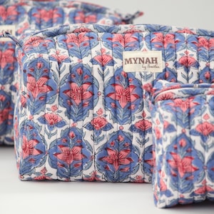 May include: Three quilted makeup bags with a floral print in shades of blue, pink, and white. The bags have a zipper closure and a label that reads "MYNAH by Smitha".