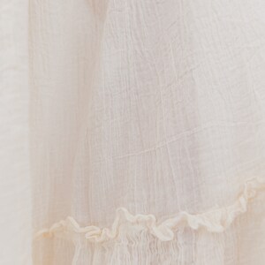May include: A white cotton skirt with a ruffled hem. The skirt is made from a lightweight fabric and has a soft, flowing texture.
