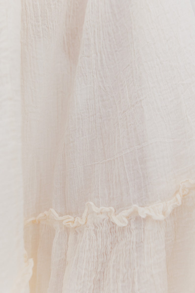 May include: A white cotton skirt with a ruffled hem. The skirt is made from a lightweight fabric and has a soft, flowing texture.