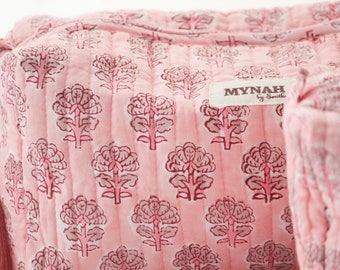 Puede incluir: Bolsa de maquillaje acolchada rosa con estampado floral y una etiqueta que dice "MYNAH by Smitha".