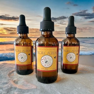 May include: Three amber glass bottles of Golden Glow Facial Serum with black droppers. Each bottle has a yellow label with the text "BEE DELICIOUS" and "ALL NATURAL". The bottles are 2 oz each.