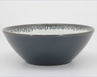 May include: A round ceramic bowl with a smooth dark charcoal exterior and a contrasting white interior. The rim features a decorative drip-glaze pattern in dark gray, creating a series of vertical streaks that extend downward into the white basin.
