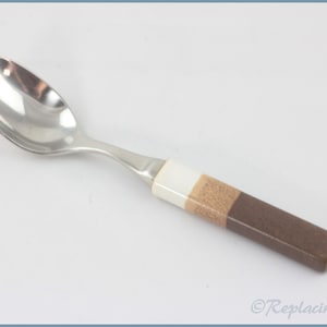 May include: A silver spoon with a brown, beige, and white handle. The handle is made of a layered material.