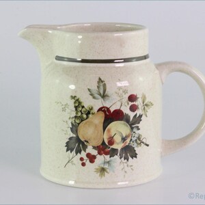 May include: A cream-colored ceramic pitcher with a brown rim and a floral design featuring pears, apples, and berries.