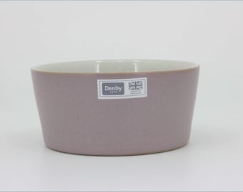 May include: A mauve ceramic bowl with a smooth matte exterior and a light speckled interior. A rectangular sticker on the front features the text Denby 1809 and a small Union Jack flag icon with the words Made in England printed below the flag.