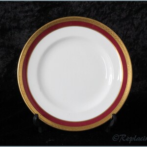 May include: A white ceramic plate with a red and gold rim. The plate has a simple design and is perfect for serving a variety of dishes.