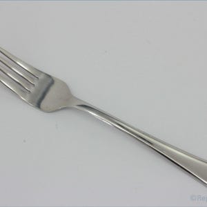 May include: A silver fork with a simple design. The fork has four tines and a long, slender handle.