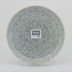May include: A round ceramic plate with a speckled grey and white finish. The centre features a square label with the text Denby 1809 Made in England and a small Union Jack flag icon. The plate has a smooth, glossy surface and a slightly raised rim.