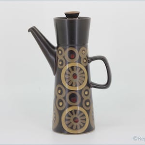 Könnte beinhalten: Eine braune Kaffeekanne aus Keramik mit einem geometrischen Muster aus Kreisen und Blumen in Braun-, Gelb- und Rottönen.