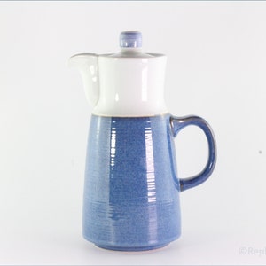 以下が含まれることがあります： 蓋付きの青と白のセラミック製のコーヒーポット。ポットは、質感のある青い釉薬と白い蓋をしています。