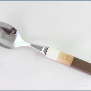 May include: A silver spoon with a brown, beige, and white handle. The handle is made of a layered material.