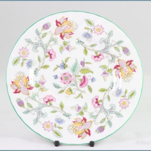 Peut inclure: Assiette en céramique blanche avec un motif floral. L'assiette a un bord vert et est ornée de fleurs roses, jaunes et bleues, ainsi que de feuillage vert et gris. Le motif floral est disposé en cercle.