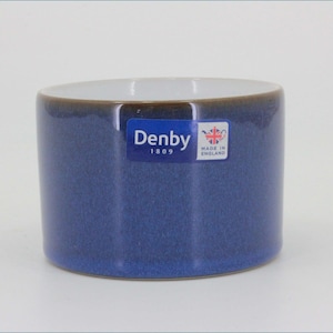 May include: A cylindrical ceramic mug with a deep blue exterior glaze and a white interior. A rectangular blue sticker on the side features the white text Denby 1809 and a small graphic of a teapot with the text Made in England.