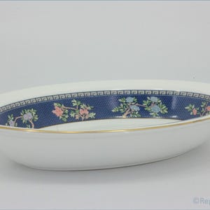 May include: Oval-shaped white serving dish with a blue floral and geometric patterned border. The dish has a gold rim and a decorative blue band with pink and blue floral accents. A classic piece for serving.