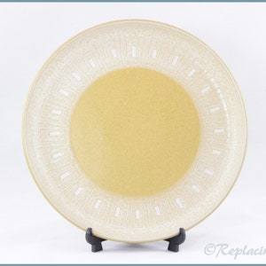 May include: A large, round, cream-coloured ceramic plate with a white geometric pattern around the edge. The plate has a yellow centre.