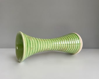 May include: A green and white ceramic vase with a ribbed design. The vase is narrow at the top and bottom, and wider in the middle.