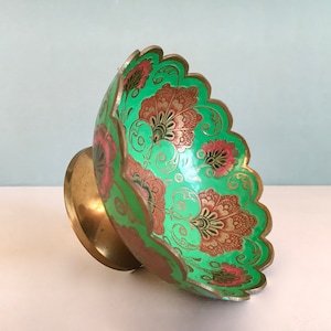 Op de afbeelding: Een koperen kom met een geschulpte rand en een levendig mintgroene geëmailleerde binnenkant, voorzien van ingewikkelde bloemmotieven in roze en gouden tinten. De kom rust op een ronde koperen voet en heeft een gepolijste metalen afwerking.
