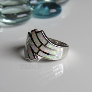 Op de afbeelding: Een zilveren ring met een witte opaal-inleg in een geometrisch ontwerp.