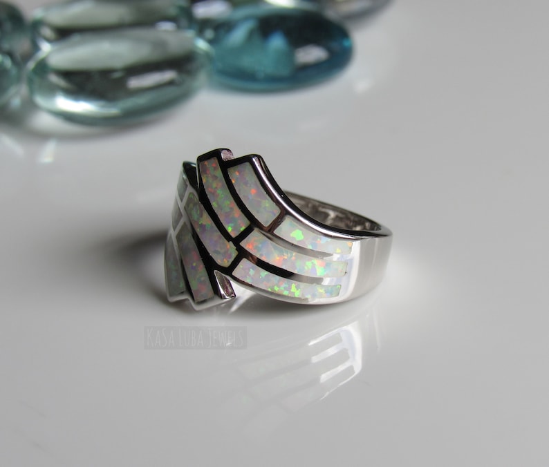 Op de afbeelding: Een zilveren ring met een witte opaal-inleg in een geometrisch ontwerp.