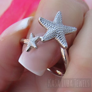 May include: Silver ring with two starfish designs. The larger starfish is on the top and the smaller starfish is on the bottom. The ring is adjustable.