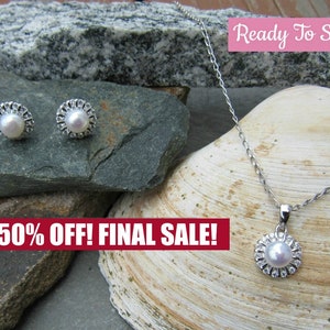 May include: A silver necklace and earrings set with a pearl and crystal accents. The necklace has a delicate chain and a pendant with a pearl in the center surrounded by crystals. The earrings are stud earrings with a pearl in the center surrounded by crystals. The jewelry is displayed on a rock and a seashell. The text "Ready To Ship" and "50% OFF! FINAL SALE!" is visible in the image.