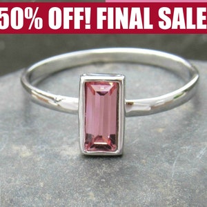 May include: A silver ring with a pink rectangular gemstone set in a silver bezel.