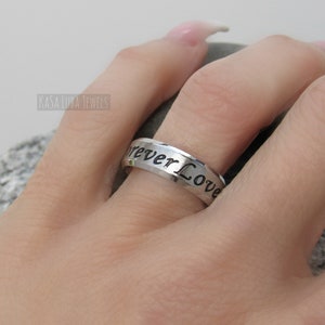 May include: A silver ring with the inscription "Forever Love" engraved on the band.