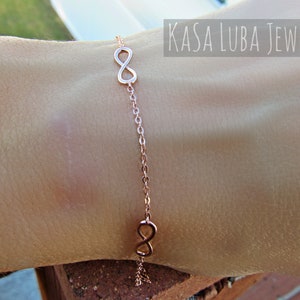 May include: A rose gold infinity symbol bracelet with two infinity symbols on a delicate chain.