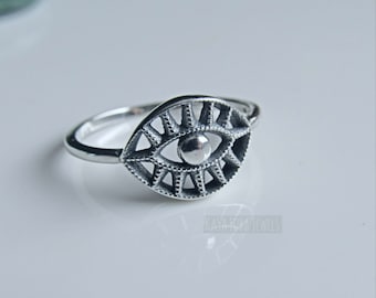 May include: Silver ring with an eye design. The eye is detailed with a circle in the center and radiating lines.
