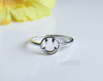 Könnte beinhalten: Ein silberner Ring mit einem Smiley-Gesichtsdesign. Der Ring ist schlicht und minimalistisch und eignet sich daher perfekt für den Alltag.