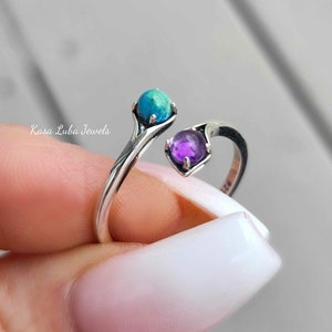 May include: A silver ring with a turquoise and amethyst stone. The ring is open and adjustable.