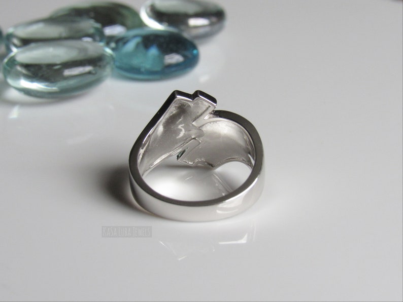 Op de afbeelding: Een zilveren ring met een bliksemontwerp. De ring wordt van achteren getoond, met de band zichtbaar.