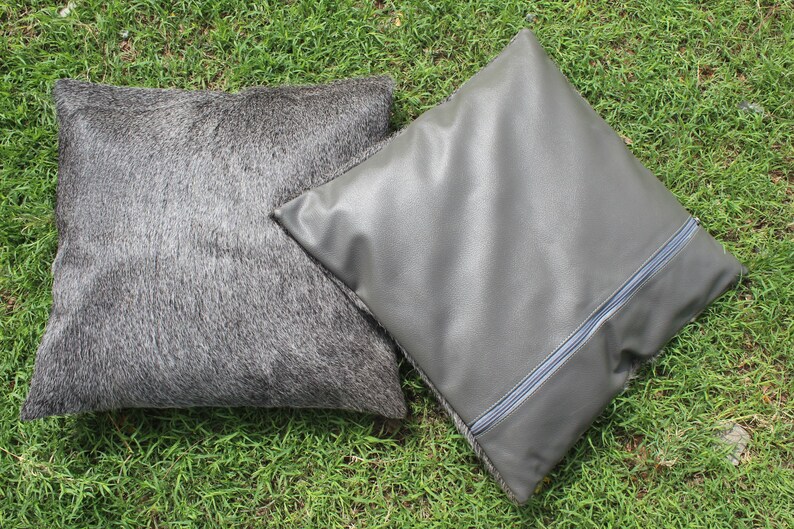 May include: Two decorative throw pillows, one gray and fuzzy, the other gray and smooth with a zipper detail.