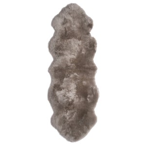 May include: A long, rectangular sheepskin rug in a light gray color. The rug has a soft, fluffy texture and is perfect for adding warmth and comfort to any room.