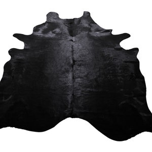 May include: Black cowhide rug with a natural, irregular shape. The hide is soft and has a subtle sheen.