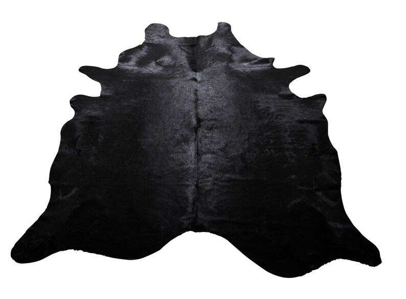 May include: Black cowhide rug with a natural, irregular shape. The hide is soft and has a subtle sheen.