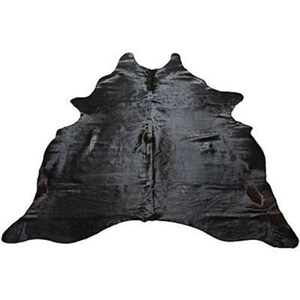 May include: Black cowhide rug with a natural, slightly distressed look. The rug has a long, flowing shape with a pointed tail.