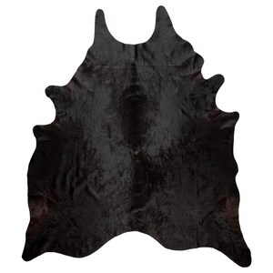 May include: Black cowhide rug with a natural, shaggy texture. The rug is approximately 5 feet by 7 feet.